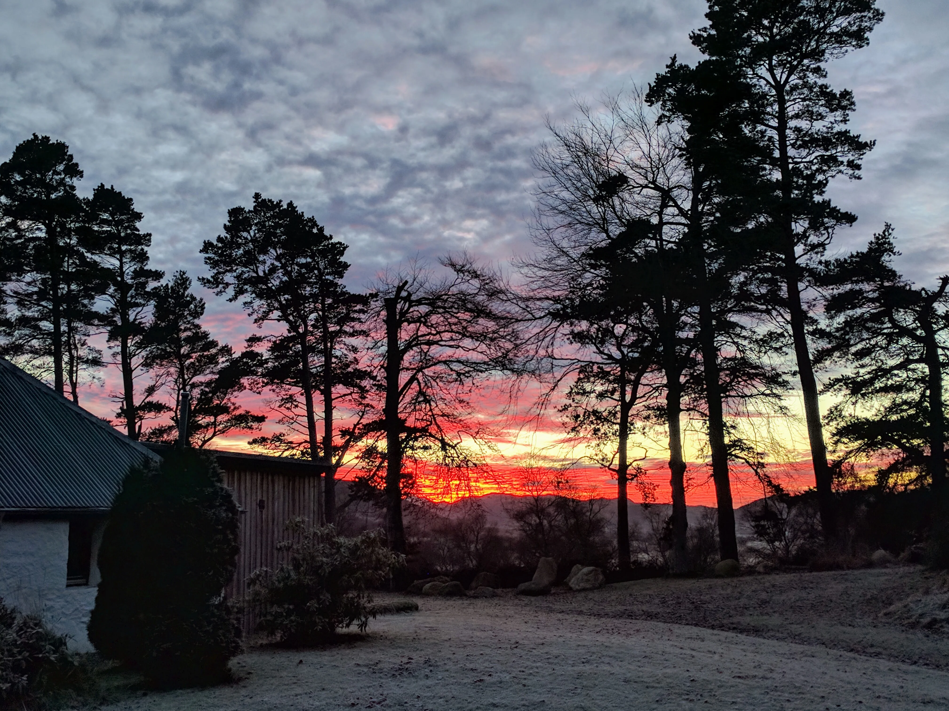 Fiery winter sunrise over the Cairngorm glen from Glentruim — deep amber sky above a dark, still landscape