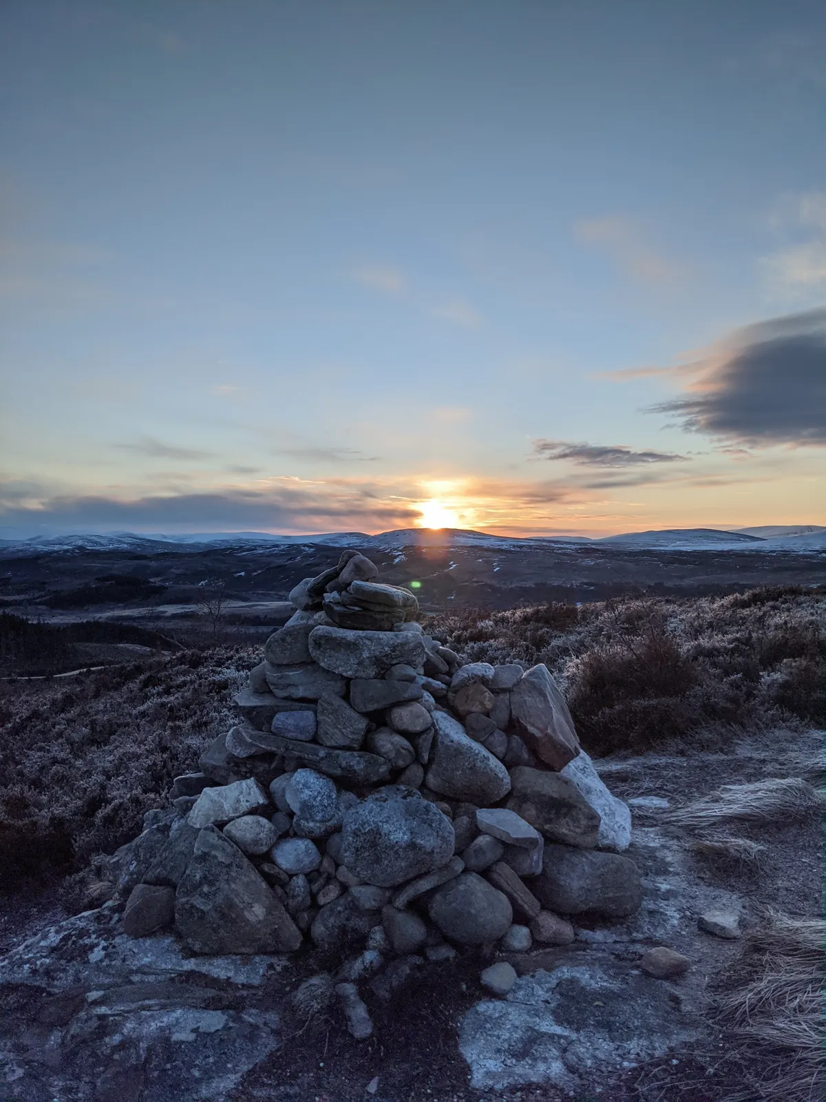 Winter sunrise at the Glentruim Viewpoint cairn, snow on the surrounding hills